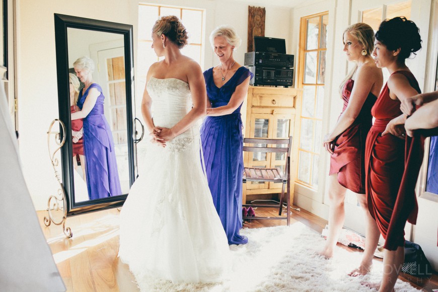 Bridal party looks on as the bride is assisted by her mother