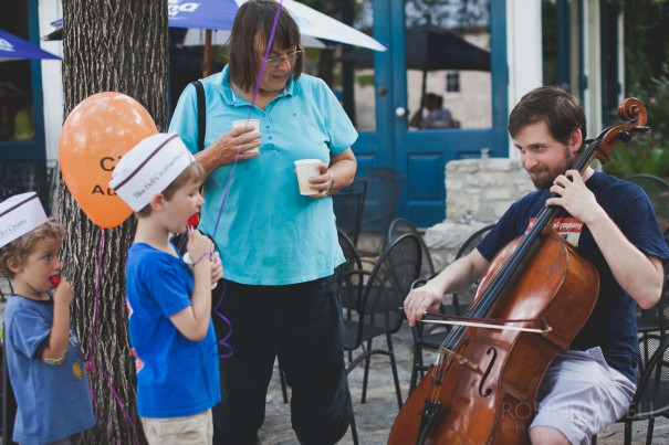 A musician demonstrates how to a play a cello to a couple of children at the Austin Symphony Orchestra "Children's Art Park"