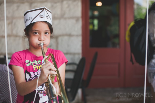 A young girl does her best trying to play a coronet at the Austin Symphony Orchestra "Children's Art Park"