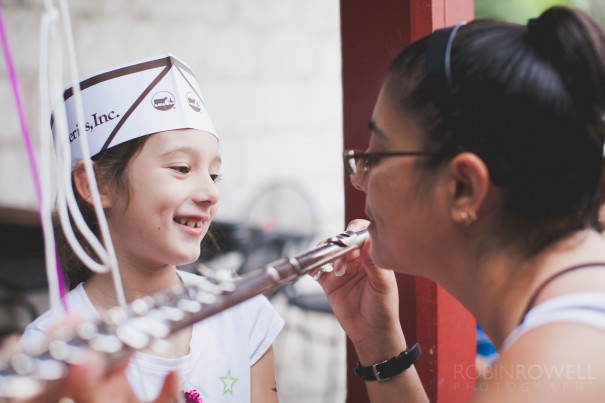 A young girl's mother demonstrates how to play a flute at the Austin Symphony Orchestra "Children's Art Park"