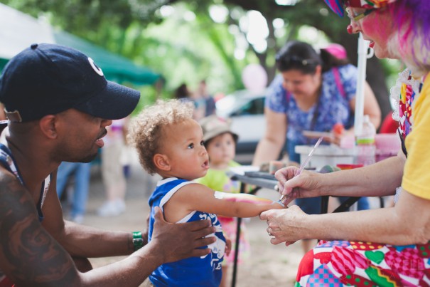 A toddler gets his hand painted while dad looks on at the Austin Symphony Orchestra "Children's Art Park"