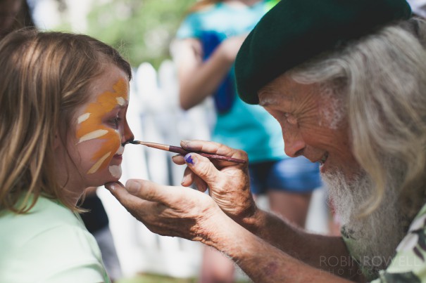 An artist carefully applies face paint to a young girl at the Austin Symphony Orchestra "Children's Art Park"