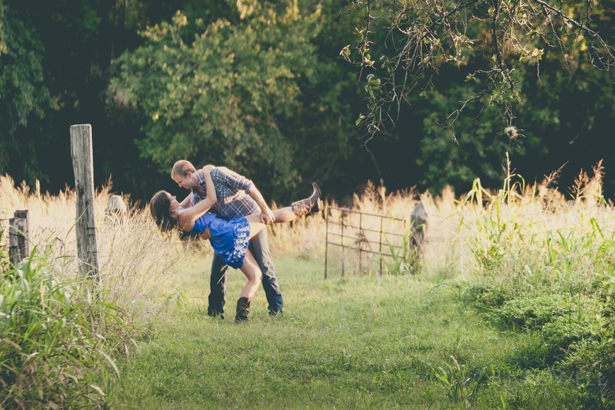 Boone dips Aubrey in a grassy field during sunset - engagement photo