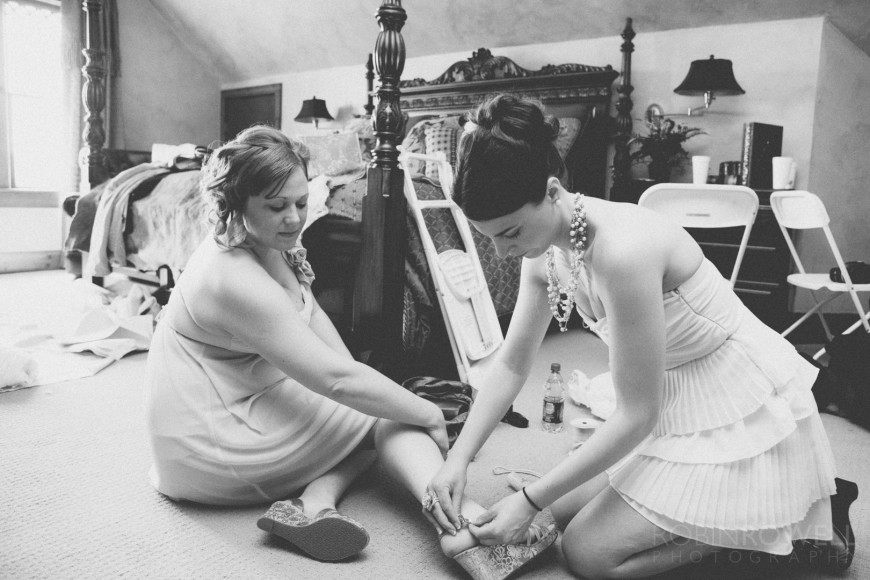 A bridesmaid helps buckle another bridesmaid's shoe - ranch style wedding in Leander, TX