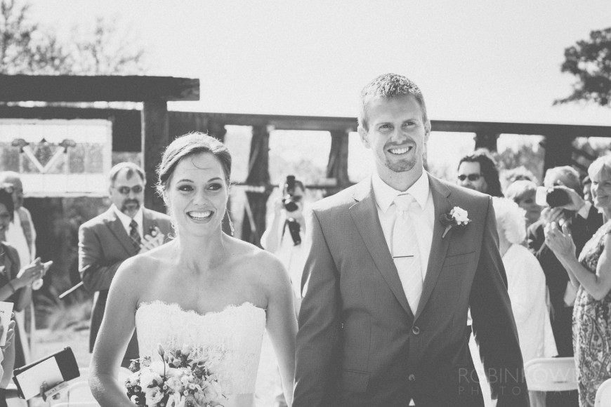 Delighted newlyweds walk past their guests - ranch style wedding in Leander, TX