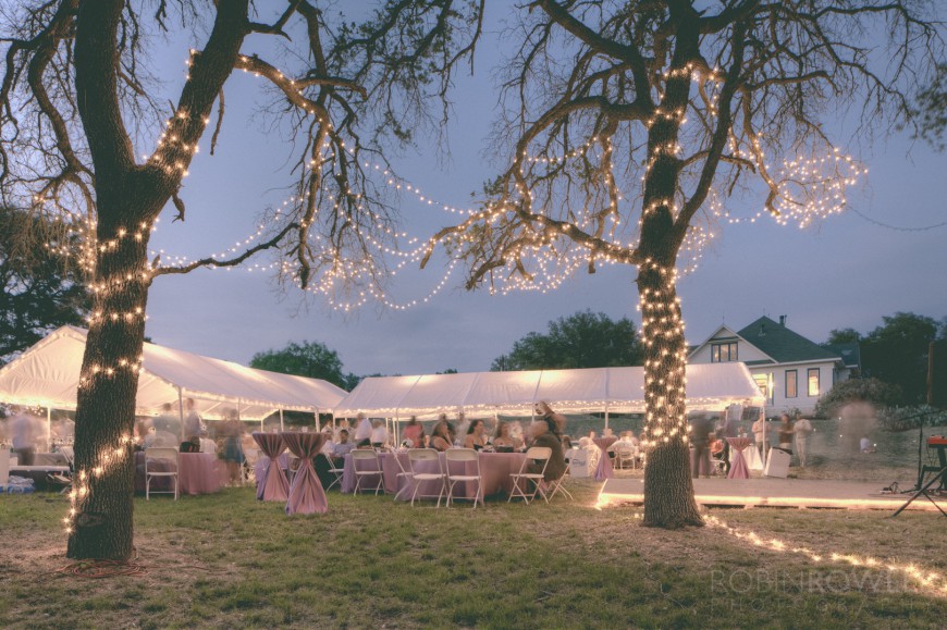 The evening settles on the reception area as lights illuminate the trees - ranch style wedding in Leander, TX