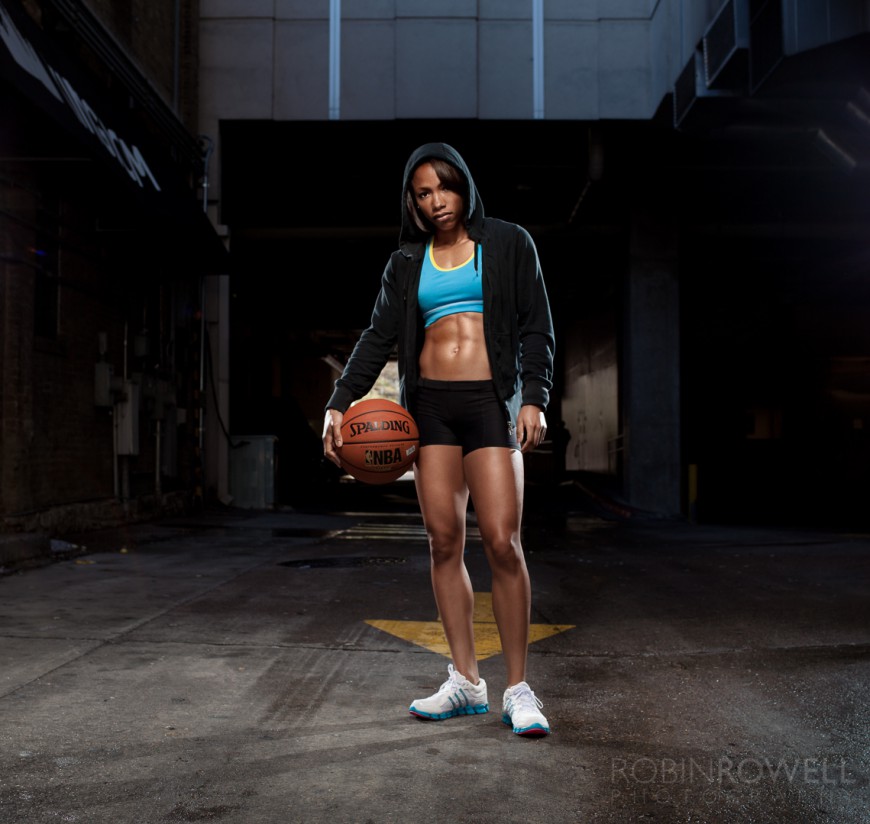Female athlete holds a basketball in urban setting