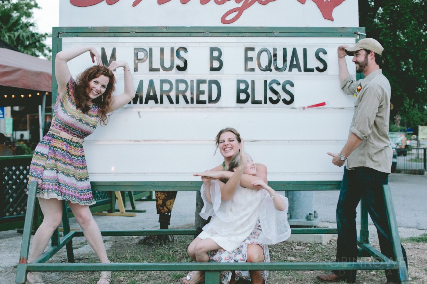 The bride, groom and a couple of family members strike silly poses in front of a marquee