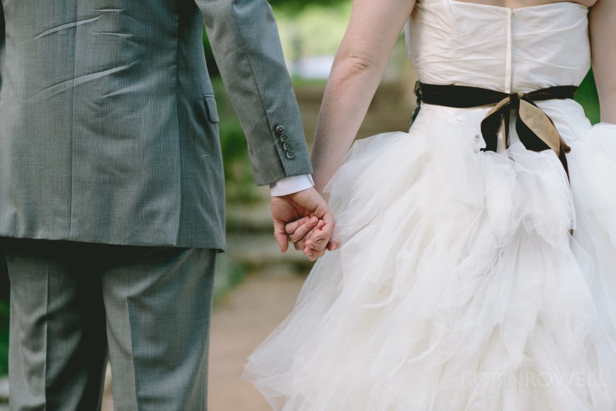 A close up photo of the groom and bride holding hands