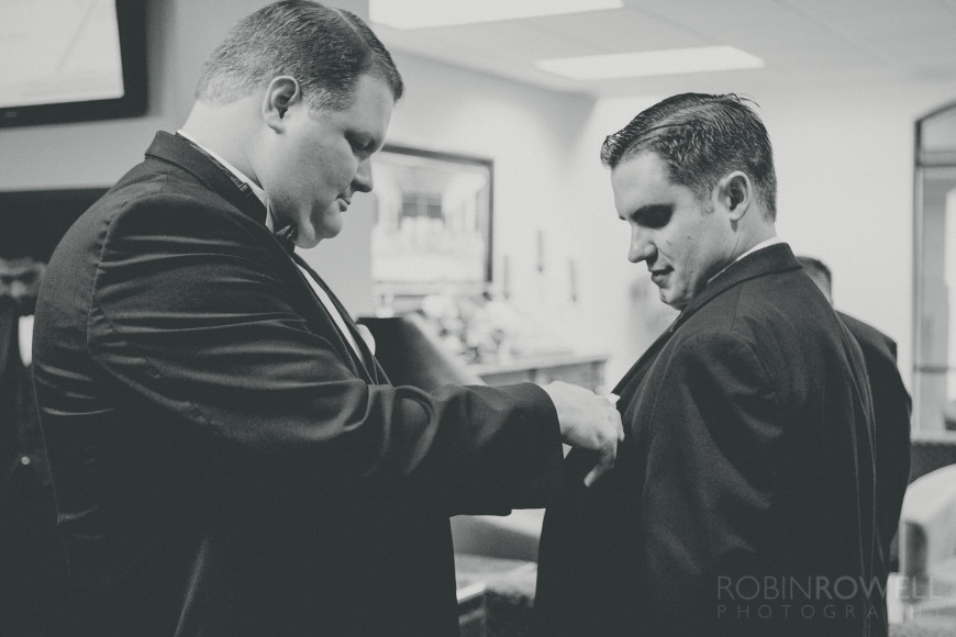 Groomsmen help each other out with the boutonnieres