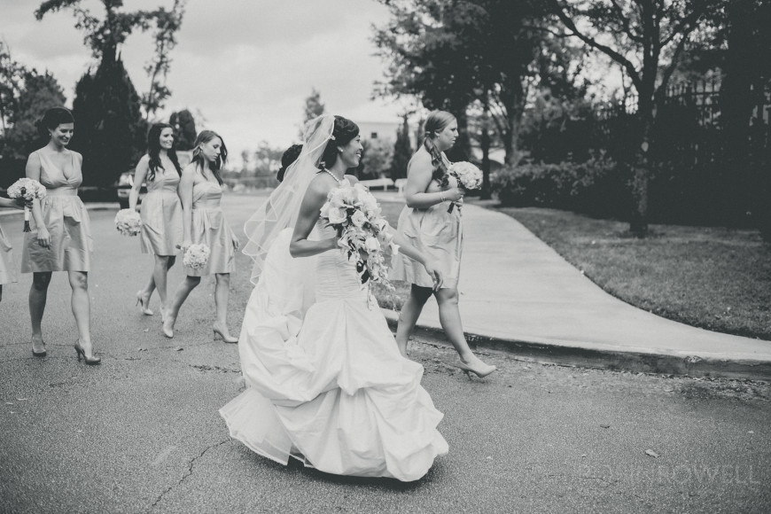 A photojournalistic style black and white of the bride and bridesmaids walking at The Woodlands United Methodist Church
