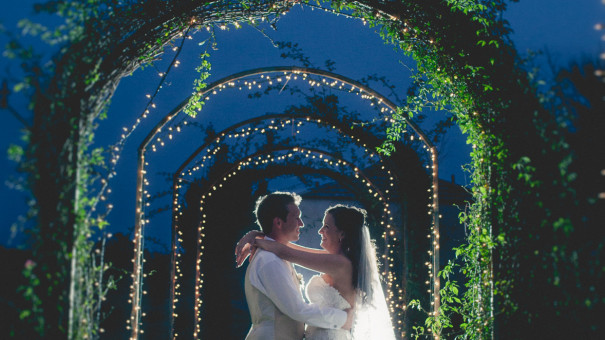 Newly married Torrey and Kennedy embrace under vine arches at Le San Michelle - Photo by Austin Wedding Photographer Robin Rowell