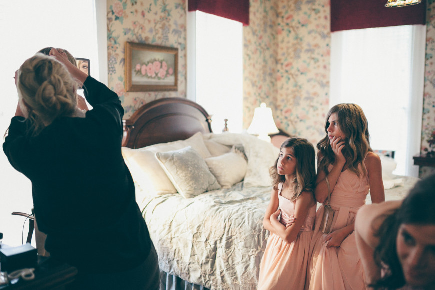 The bride's younger sisters watch as a hair clip is applied